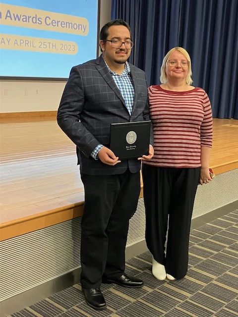 Julie with a student holding a certificate at an awards ceremony