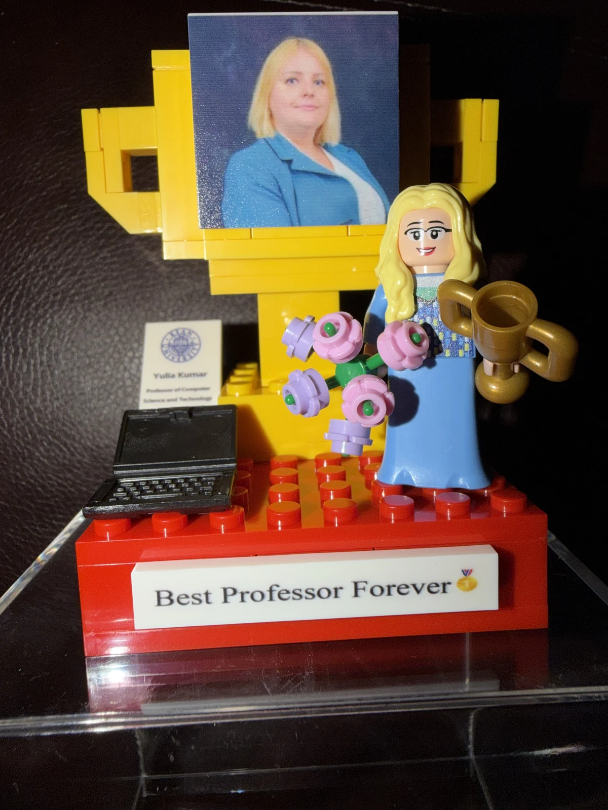 LEGO Julie Best Professor Forever display with a minifigure, flowers, trophy, miniature computer, and Julie's portrait